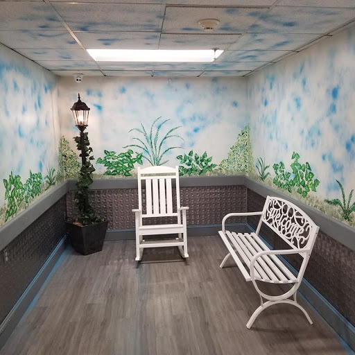A cozy indoor seating area featuring artistic wall murals and potted plants.