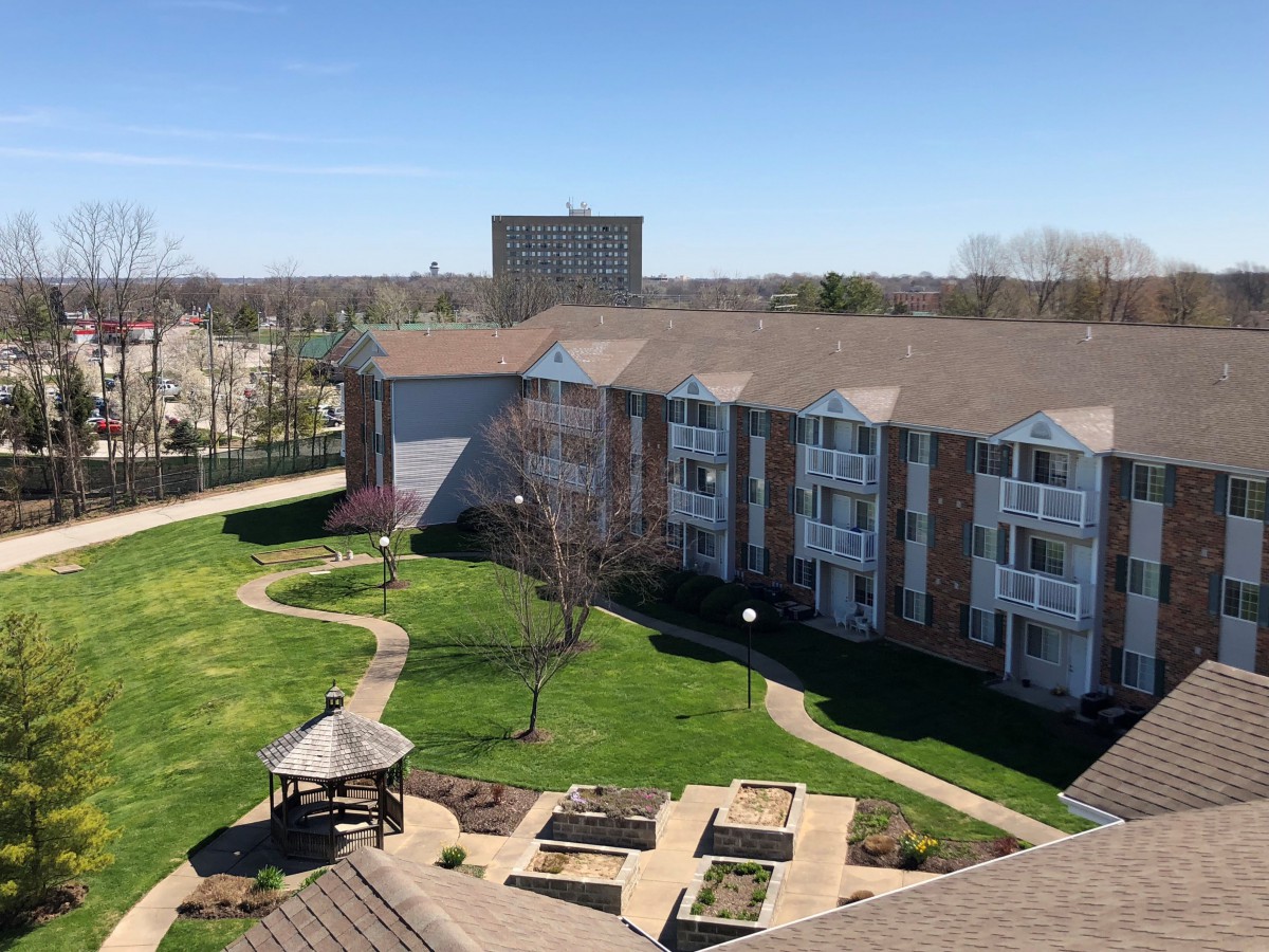 Aerial view of a residential apartment complex with landscaped gardens and a central gazebo.