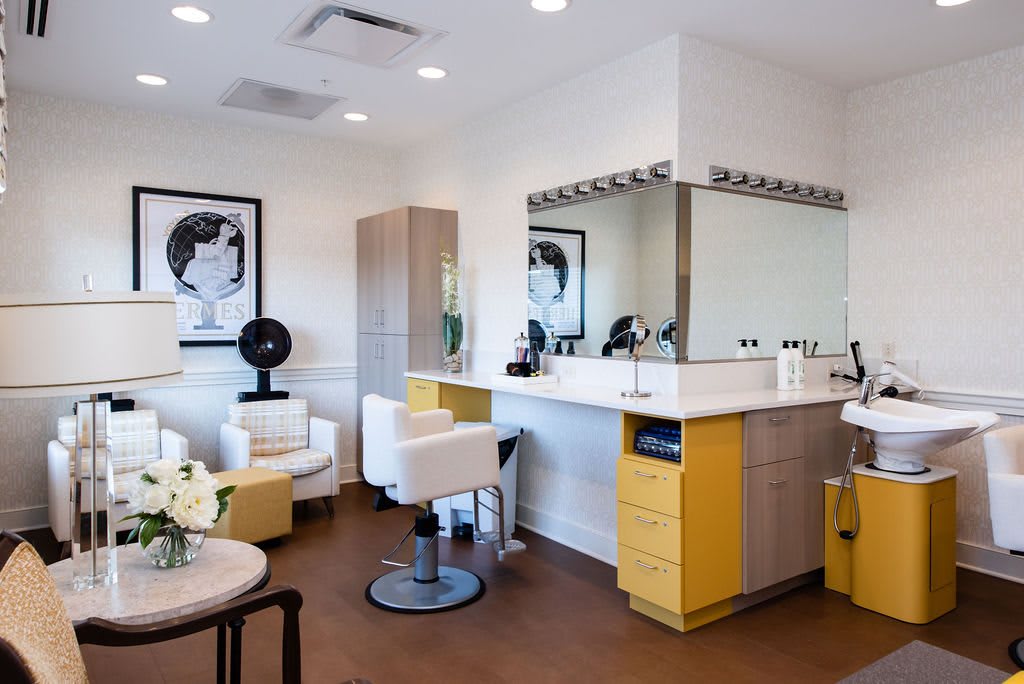 A modern beauty salon interior with styling chairs and mirrors, featuring bright lighting and contemporary artwork.
