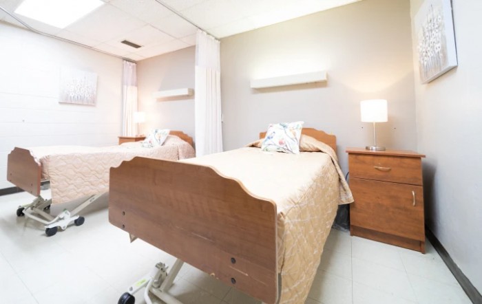 A clean and organized hospital room with two patient beds and warm lighting.