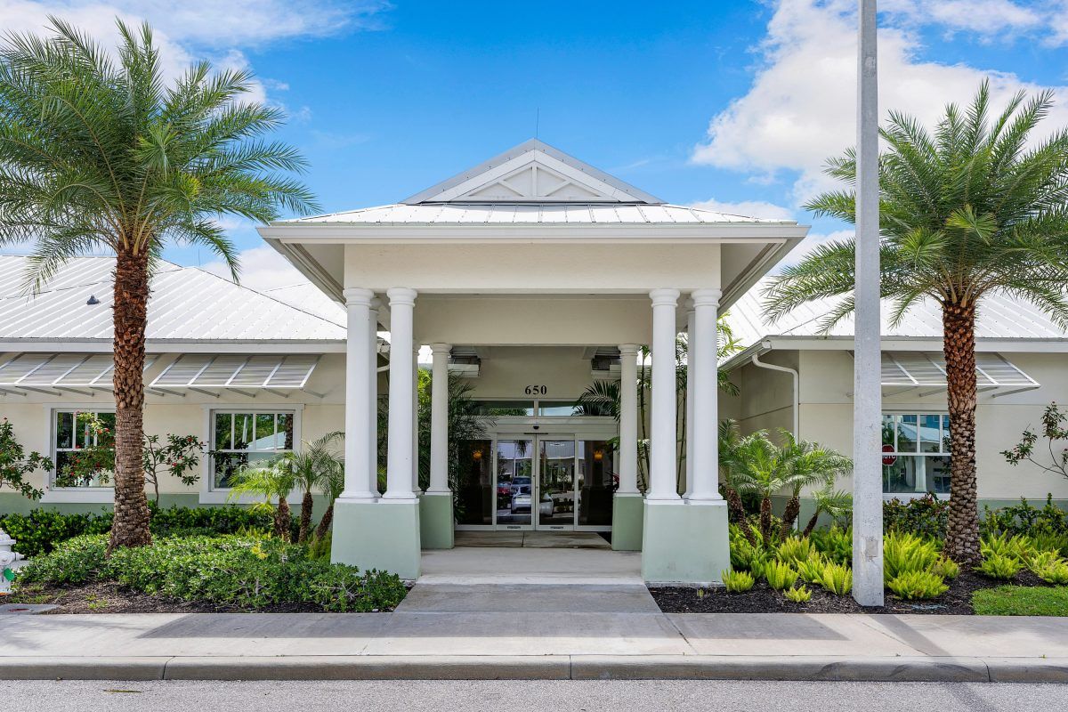 A resort entrance with tropical landscaping and clear blue skies.