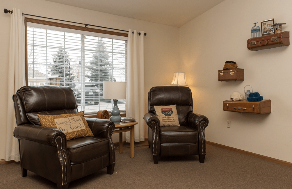 A cozy living room with two reclining chairs and a large window.