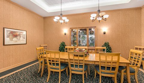 A traditional dining room featuring a wooden table and chairs, with elegant chandeliers and decorative elements.