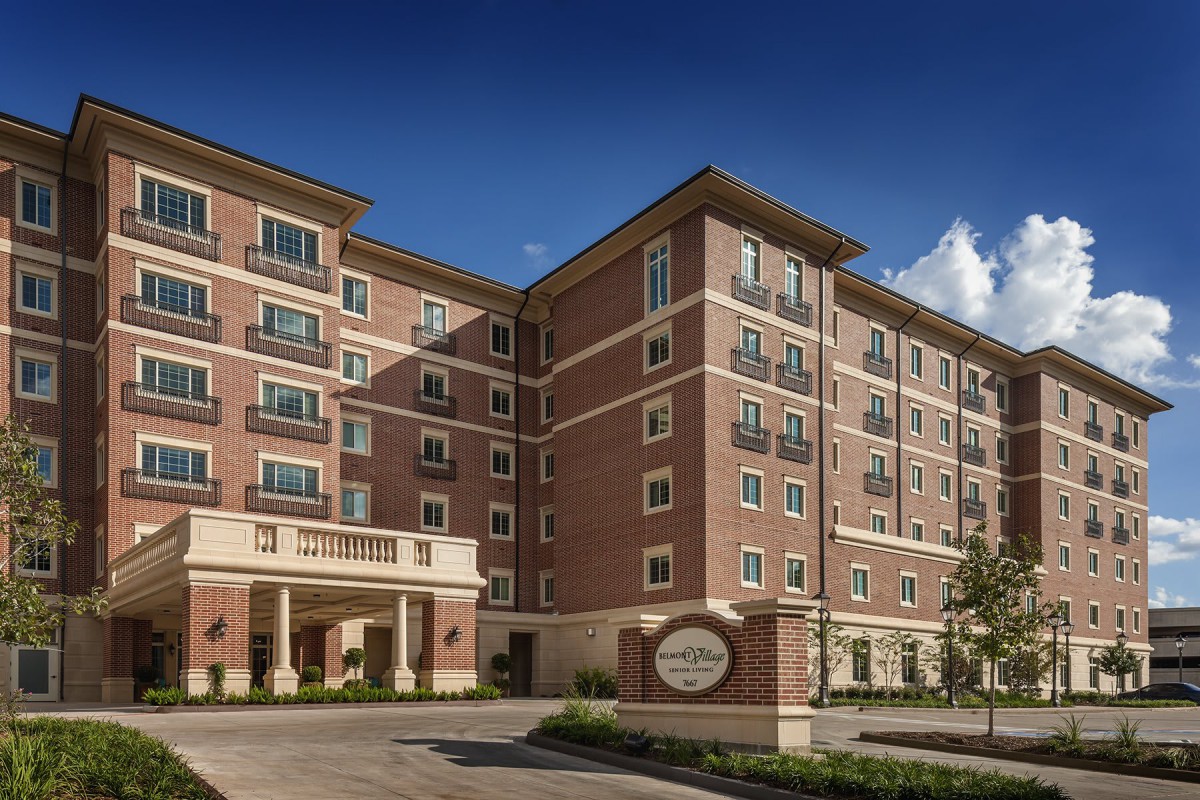 A multi-story hotel building with a brick exterior under a clear blue sky.