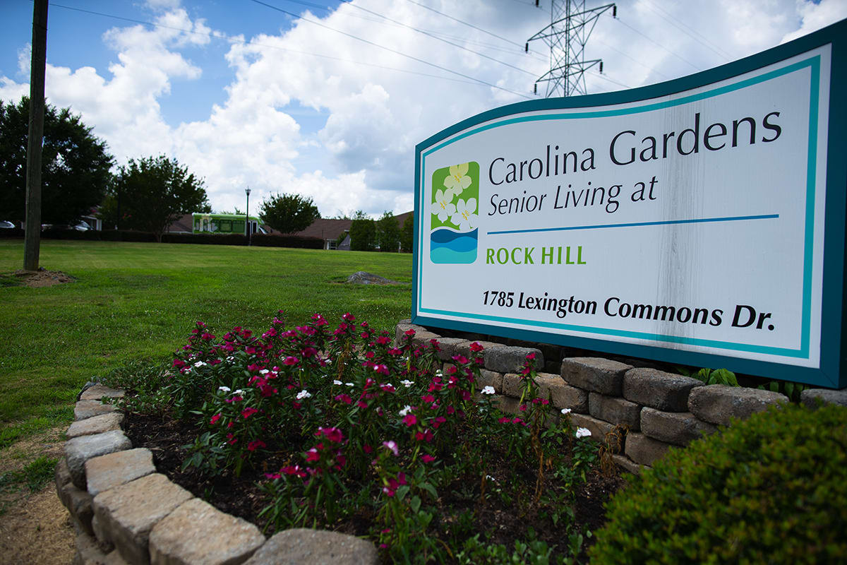 Entrance sign for Carolina Gardens Senior Living at Rock Hill, surrounded by well-maintained landscaping and flowers.