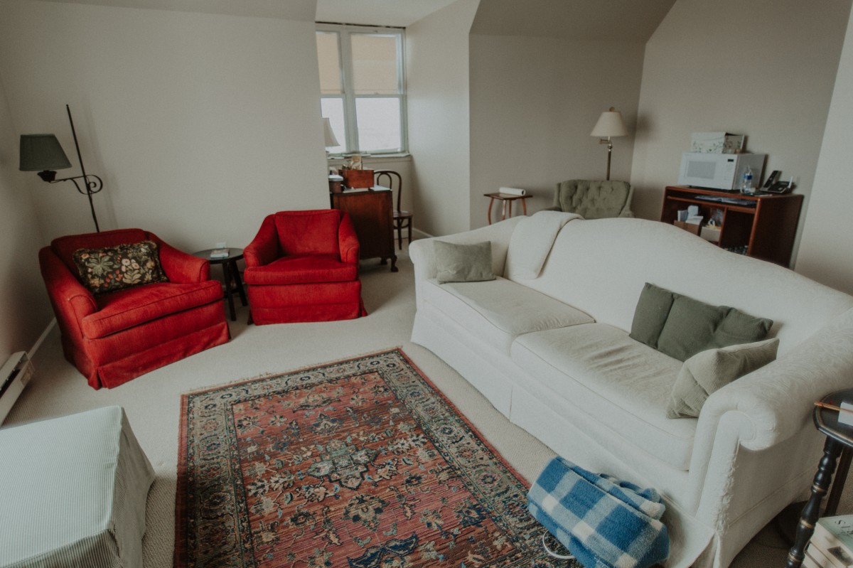 A cozy living room with a white sofa, red armchairs, and a patterned carpet.
