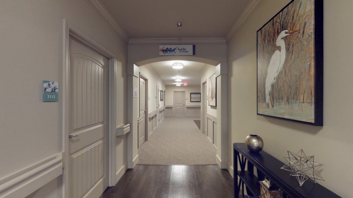 A well-lit hallway with artwork on the walls and doors lining both sides.
