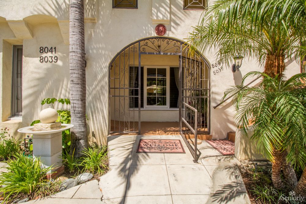 A sunlit entrance with an archway surrounded by palm trees.