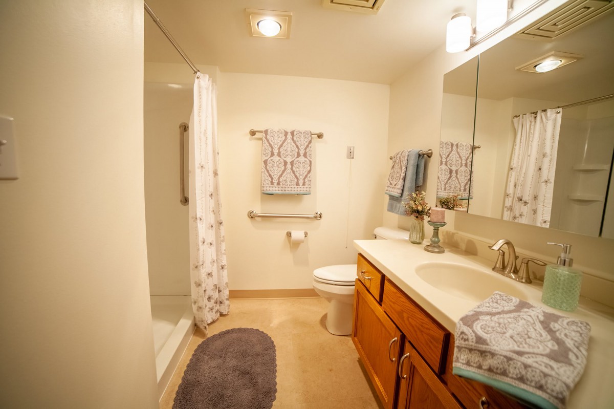 A modern bathroom with a shower, vanity, and neatly arranged towels.