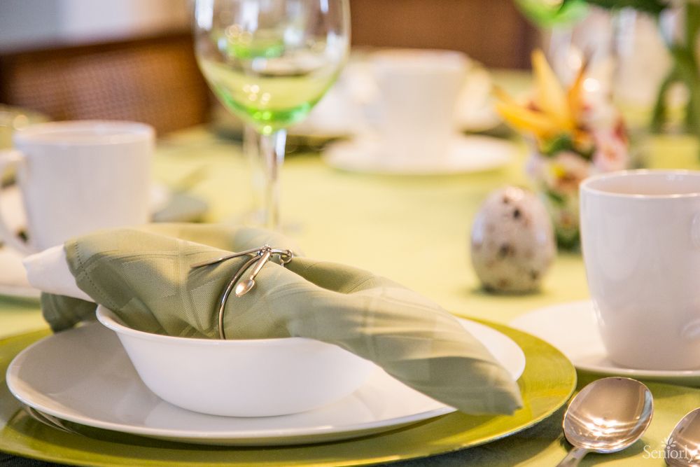 An elegant table setting with a plate, napkin, wine glass, and decorative egg.