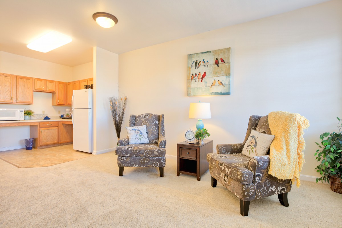A cozy living room with patterned armchairs, a side table, and warm lighting.