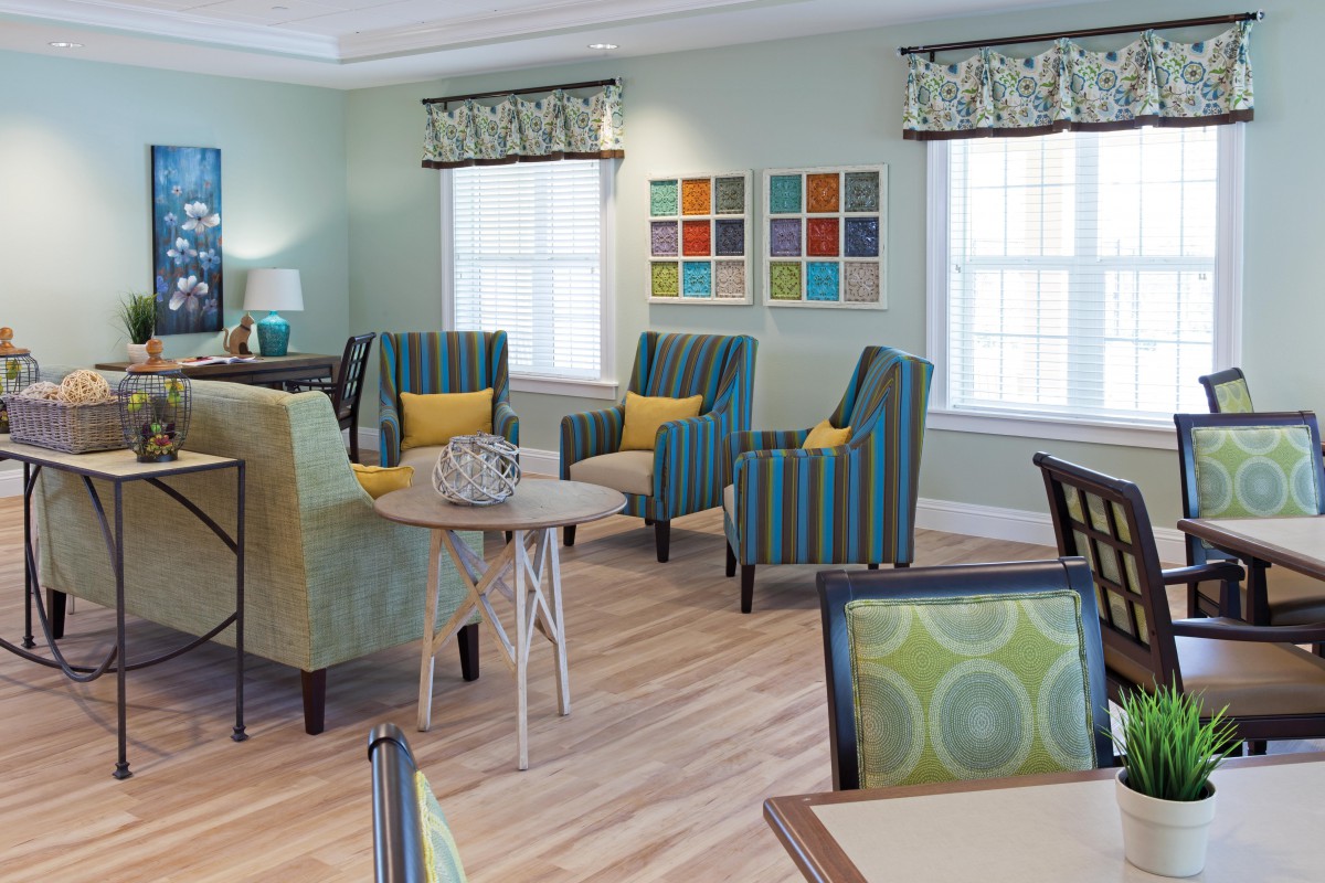 A modern living room with colorful chairs, tables, and wall art.