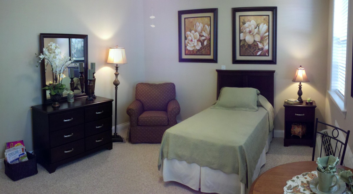 A cozy bedroom with a single bed, a chair, and decorative art on the wall.