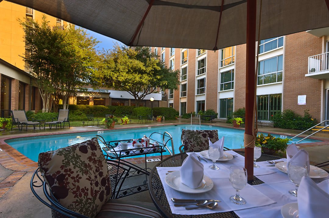 A luxurious outdoor dining area next to a serene swimming pool at a hotel.