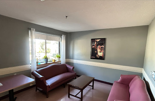 A cozy living room featuring two red couches, a coffee table, and bright natural light coming through the window.