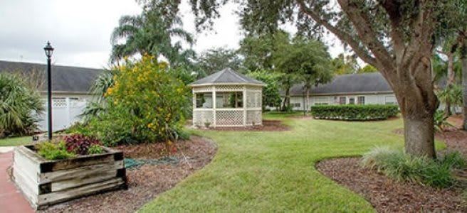 A scenic garden featuring a charming gazebo surrounded by lush greenery and trees.