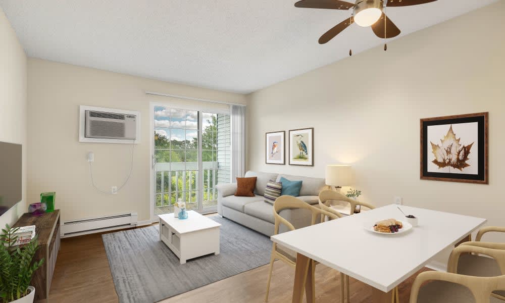 A cozy living room in an apartment featuring a sofa, coffee table, dining area, and a large window.