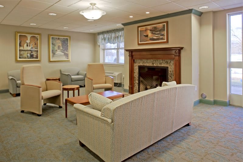 A cozy living room with comfortable seating and a fireplace, adorned with artwork.