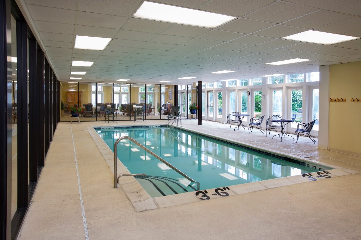 An indoor swimming pool with surrounding seating and large windows.