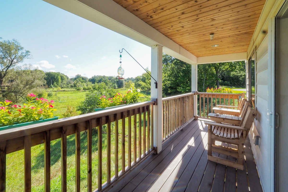 A sunny porch overlooking a lush green landscape.
