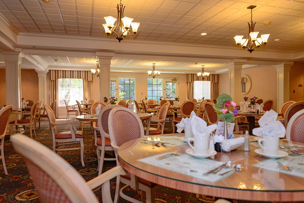 An elegant dining room with neatly set tables and chandeliers.