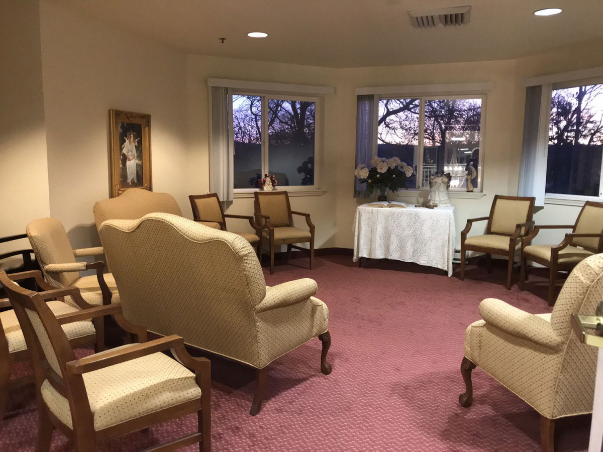 A cozy waiting room with upholstered chairs, red carpet, and large windows.