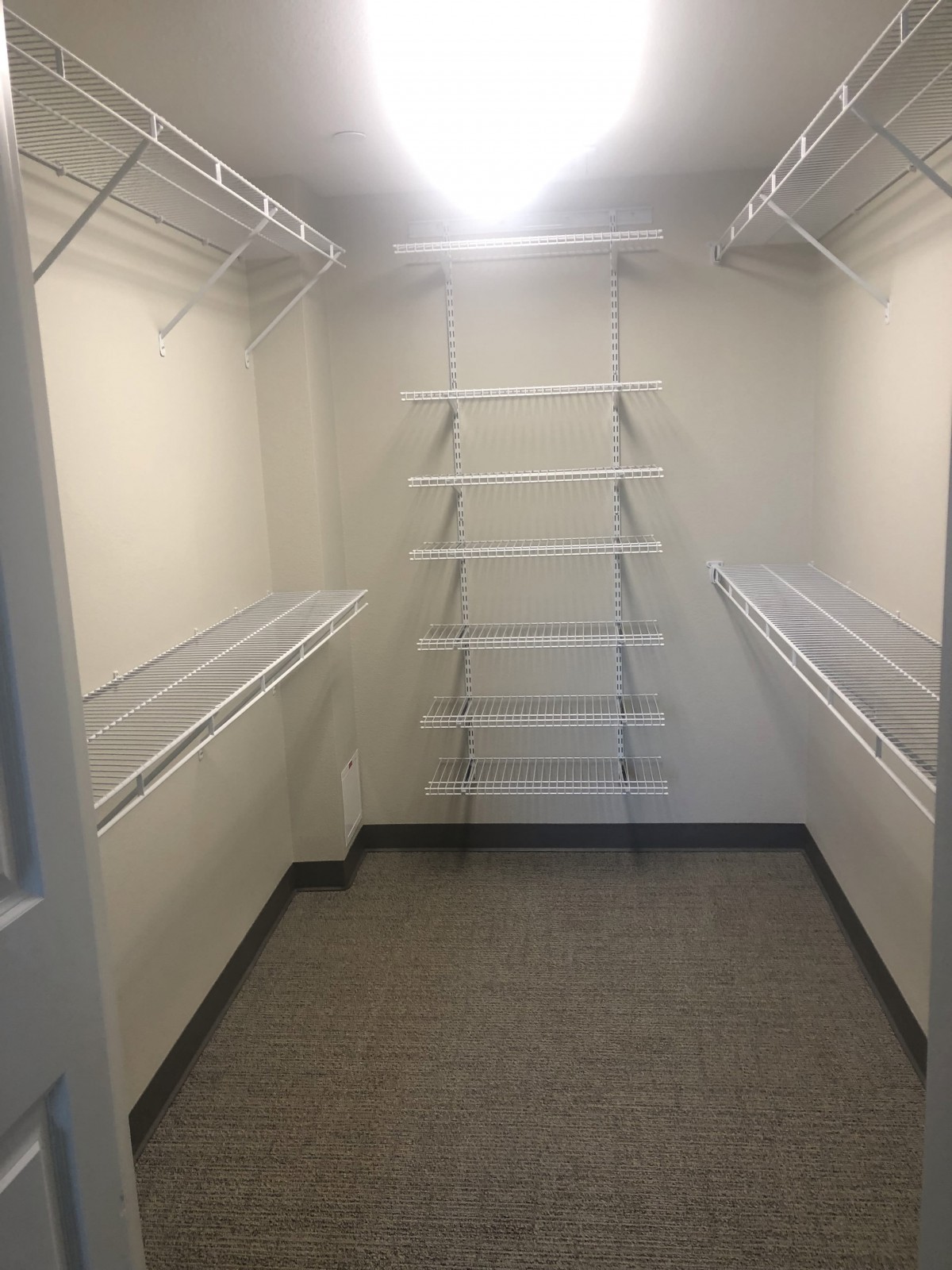 An empty walk-in closet with shelving units and hanging rods.