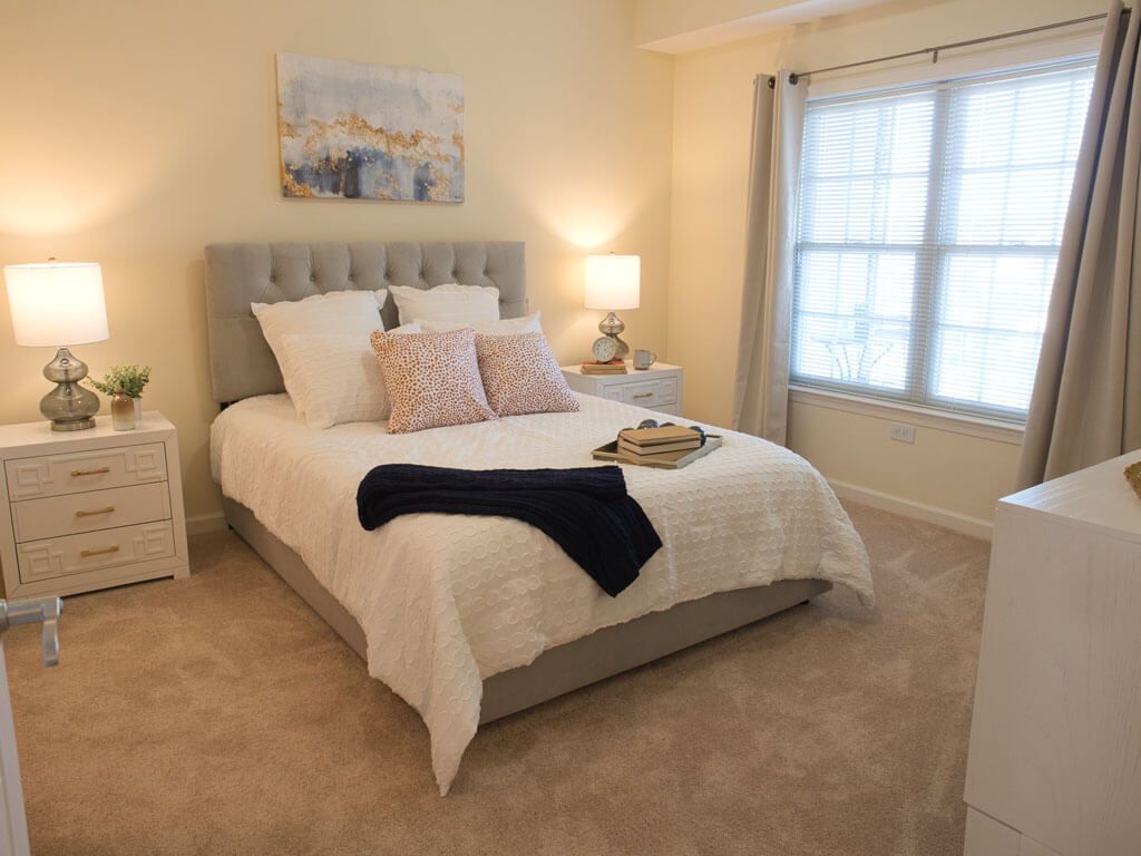 A cozy and well-decorated bedroom with a neatly made bed, bedside tables, and soft lighting.
