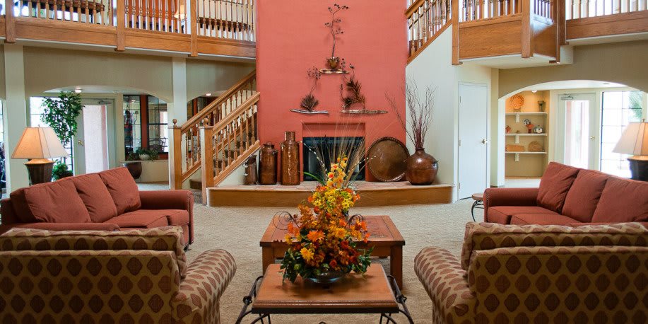 A cozy living room featuring a central fireplace, autumn-themed decorations, and comfortable seating.