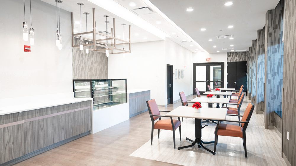 A modern, minimalist cafe interior with several empty tables and chairs.
