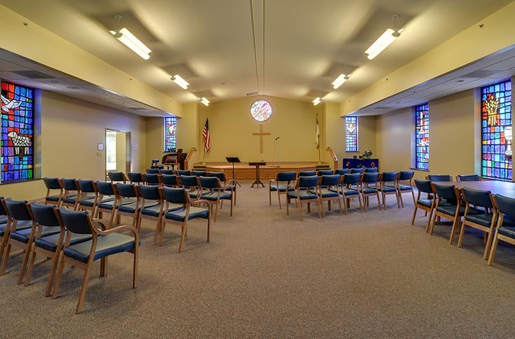 An interior view of a chapel with arranged seating and a central pulpit.