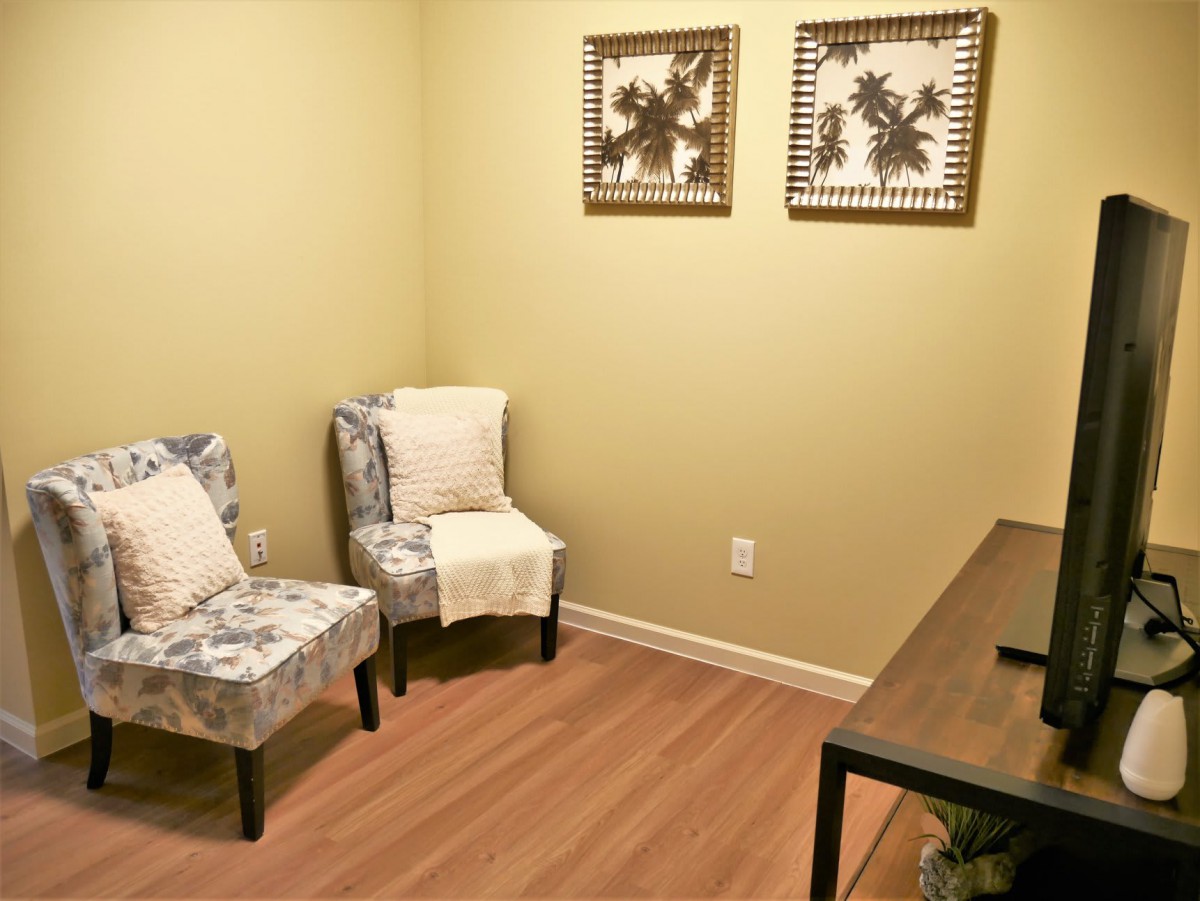 A minimalist office space with chairs, a desk, and framed artwork.