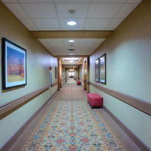 A long hallway with patterned carpet and framed art on the walls.