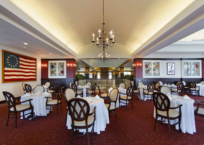 An elegant dining room setup with neatly arranged tables and chairs beneath a chandelier.