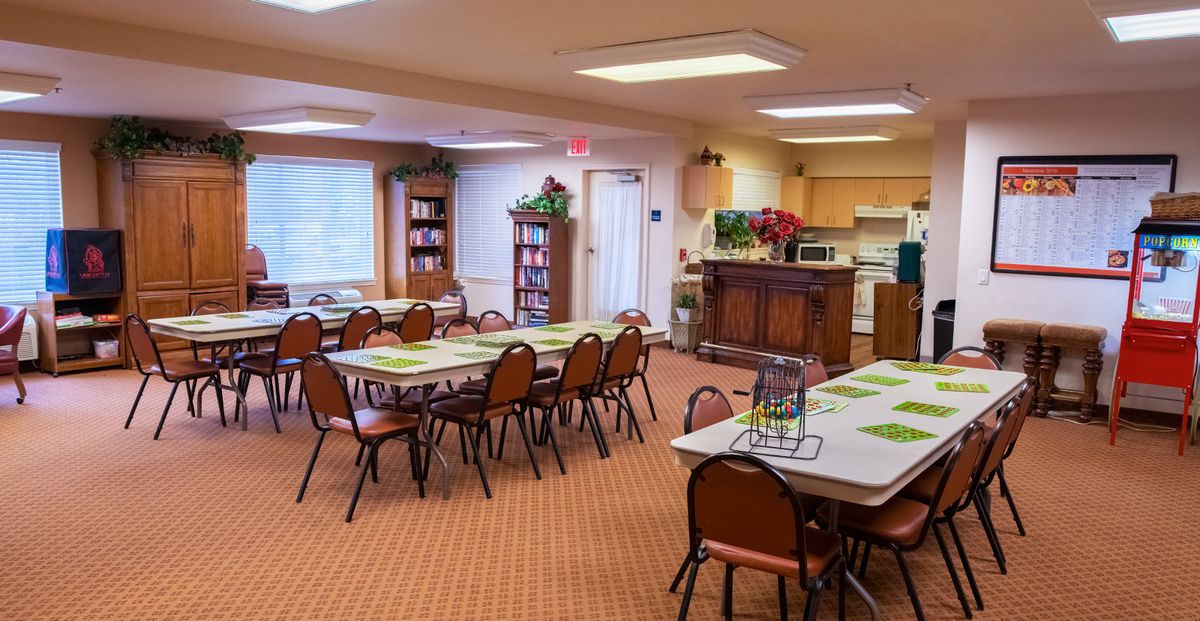 A community dining and meeting room with tables, chairs, and kitchen facilities.