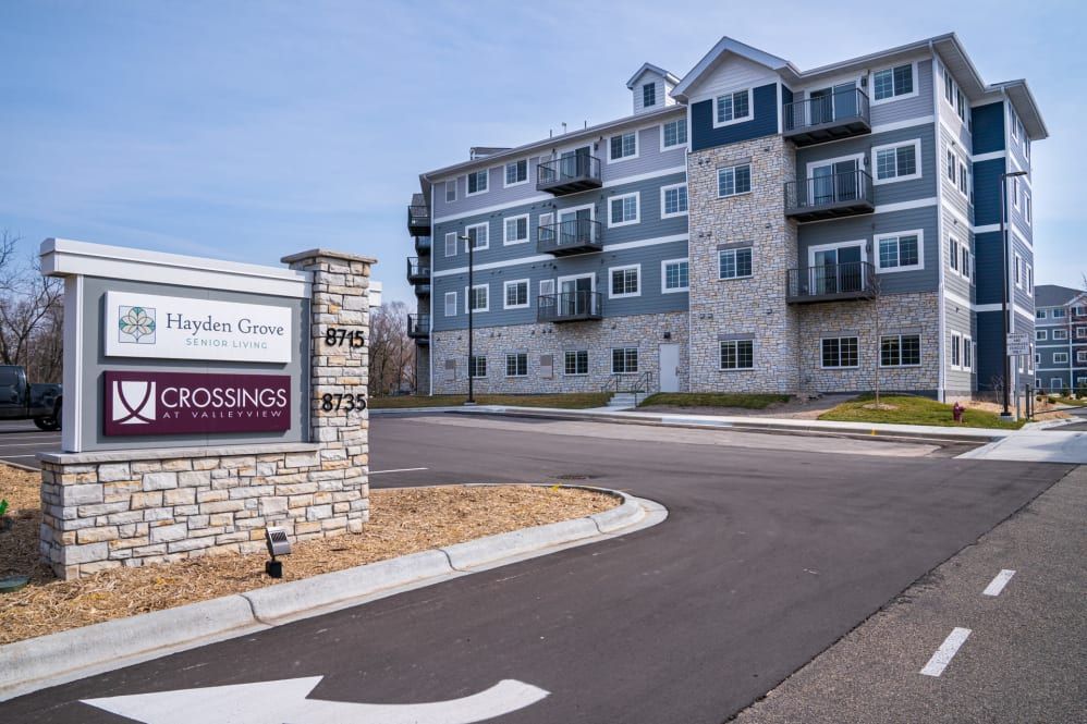 A modern apartment complex with a prominent entrance sign in an urban setting.