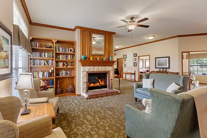 A cozy living room with a fireplace and bookshelves, featuring comfortable seating and warm decor.