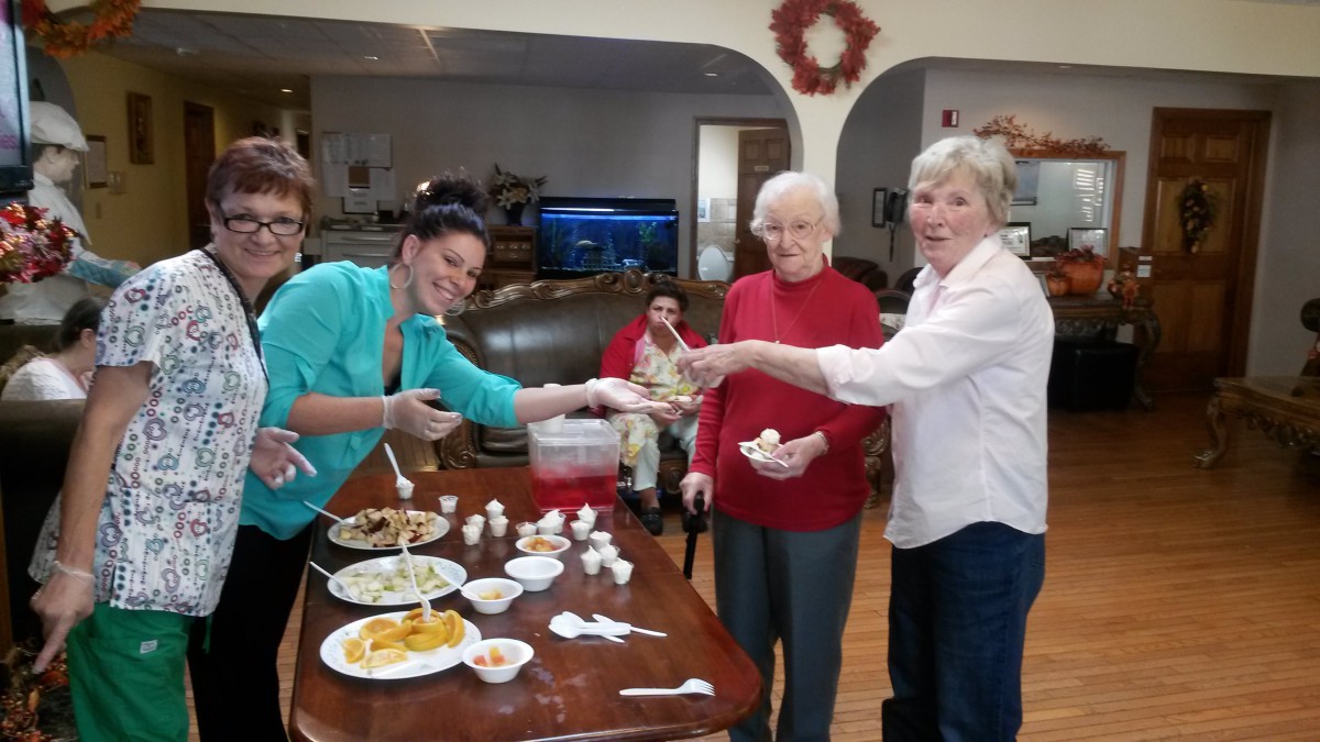 A group of people enjoying food together indoors, smiling and serving themselves from a table filled with dishes.