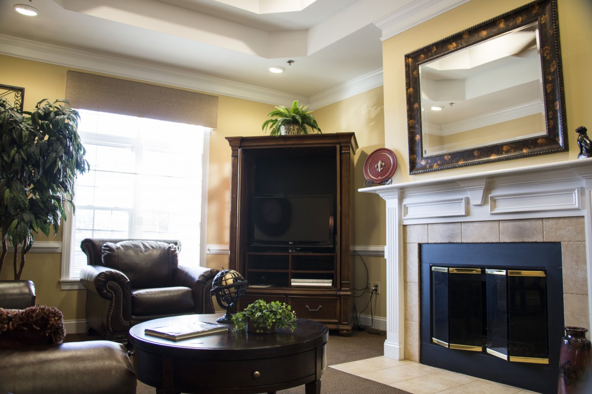 A cozy living room featuring a sofa, fireplace, and TV cabinet, accentuated by a large mirror and decorative elements.