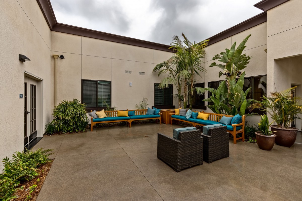 A cozy outdoor courtyard with comfortable seating and lush potted plants.