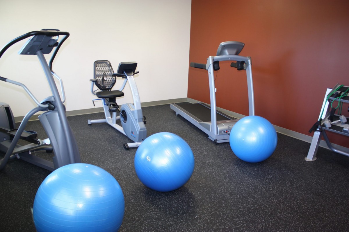 A small gym area with a treadmill, exercise bike, and blue yoga balls.