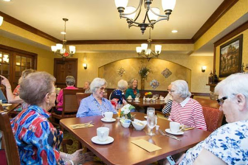 Seniors enjoying a social gathering over tea in a warm and inviting dining area.