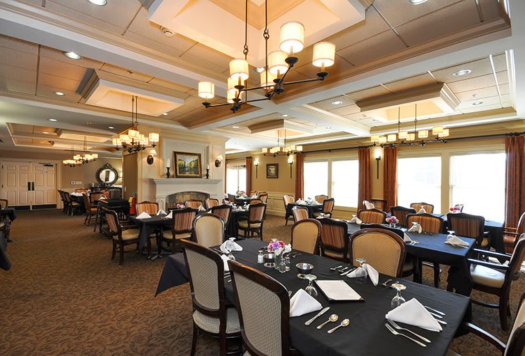 An elegant dining room with neatly arranged tables and chandeliers.