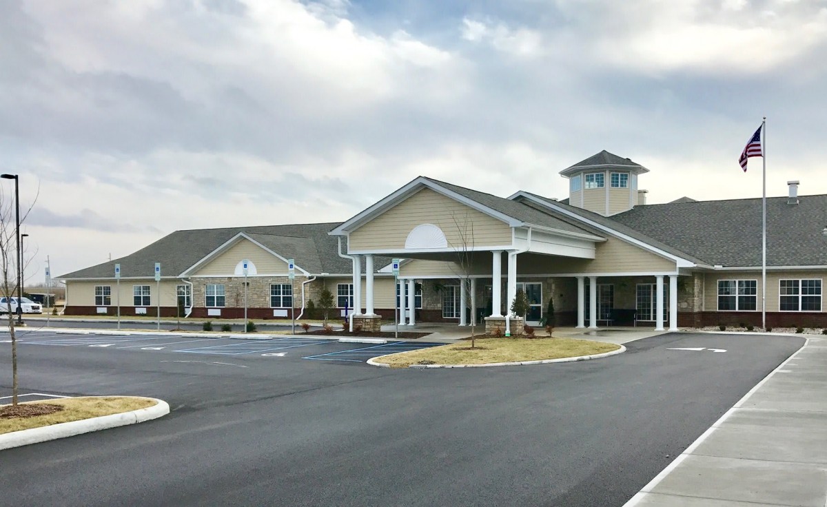 A large, modern building with a spacious parking lot under a cloudy sky.