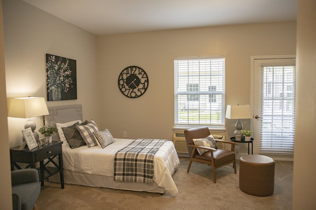 A cozy bedroom with a bed, chair, and decorative elements.