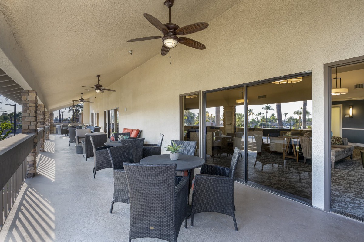 A spacious outdoor patio with wicker furniture and ceiling fans, perfect for relaxing or dining.