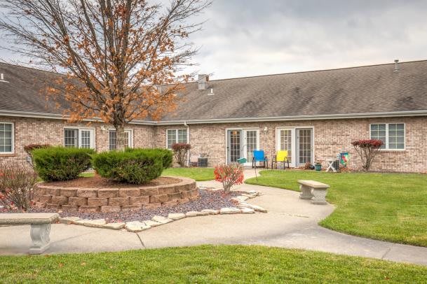 A cozy backyard with a tree and seating area, featuring a landscaped garden and paved pathway.