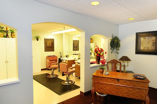 A well-lit salon interior with styling chairs and a reception desk adorned with flowers.
