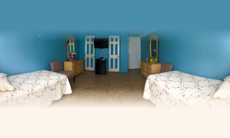 A hotel room featuring two beds, wooden furniture with mirrors, and a flat-screen TV mounted on the wall.
