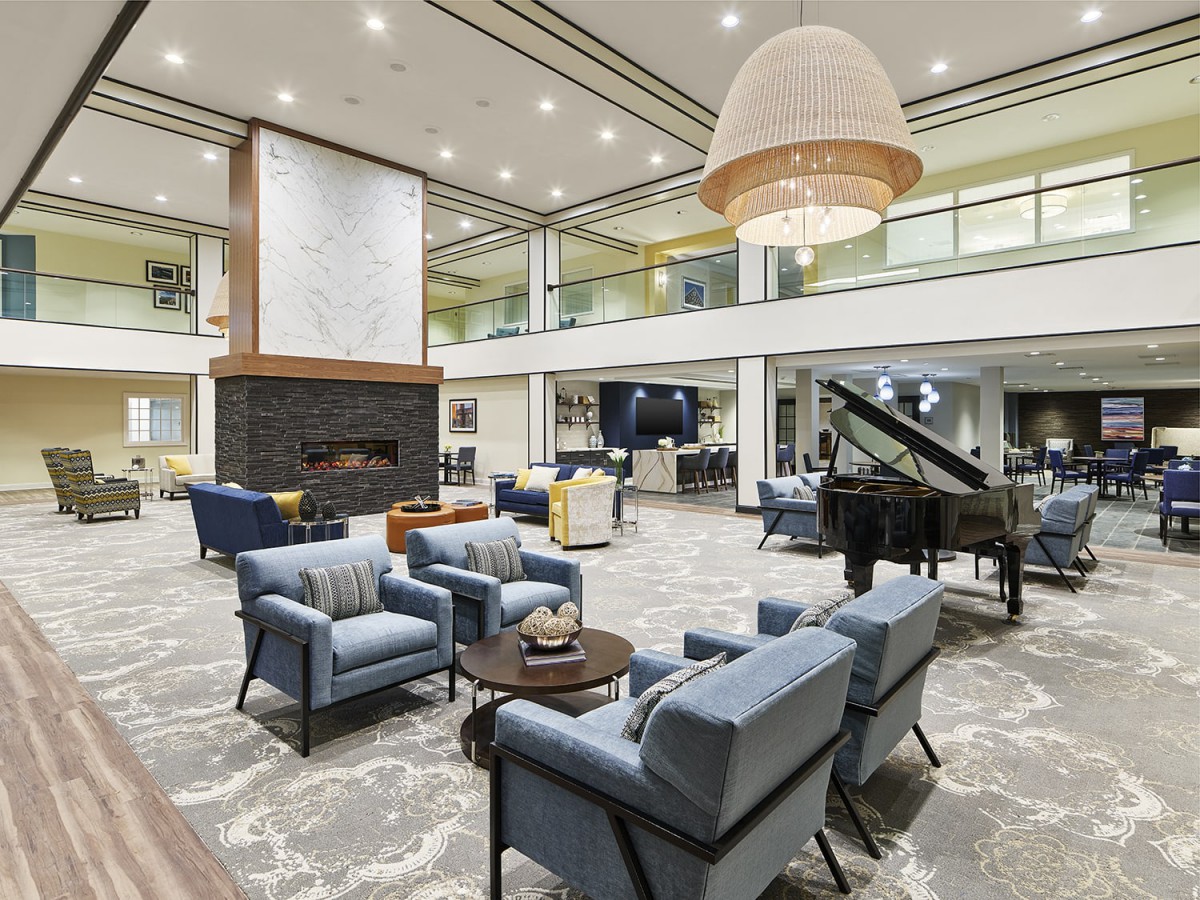 A spacious and elegantly designed lounge with comfortable seating, a fireplace, and a grand piano.
